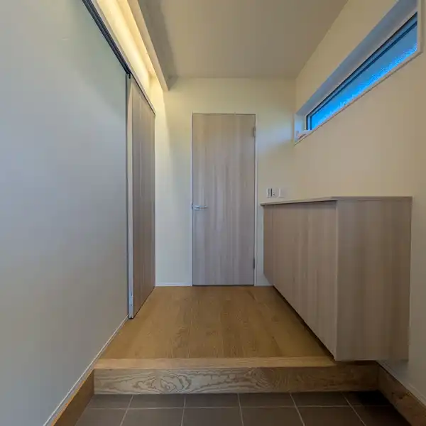 「大瀬の家」の玄関ホール。床板には亀甲なぐり加工の無垢栗フローリングを採用。壁はしっくい仕上。間接照明がしっくいやなぐりの床を柔らかく照らしてくれます。