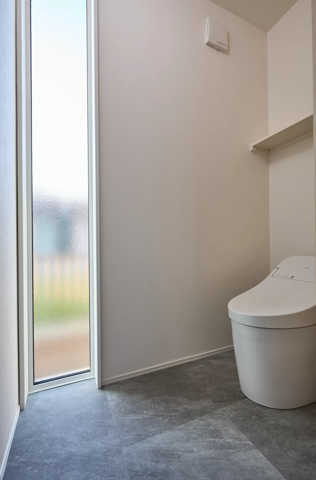 トイレの窓が特徴です。床から天井までのFIX窓です。便器はTOTO製。便器背面に棚を設えちょっとした収納になっています。