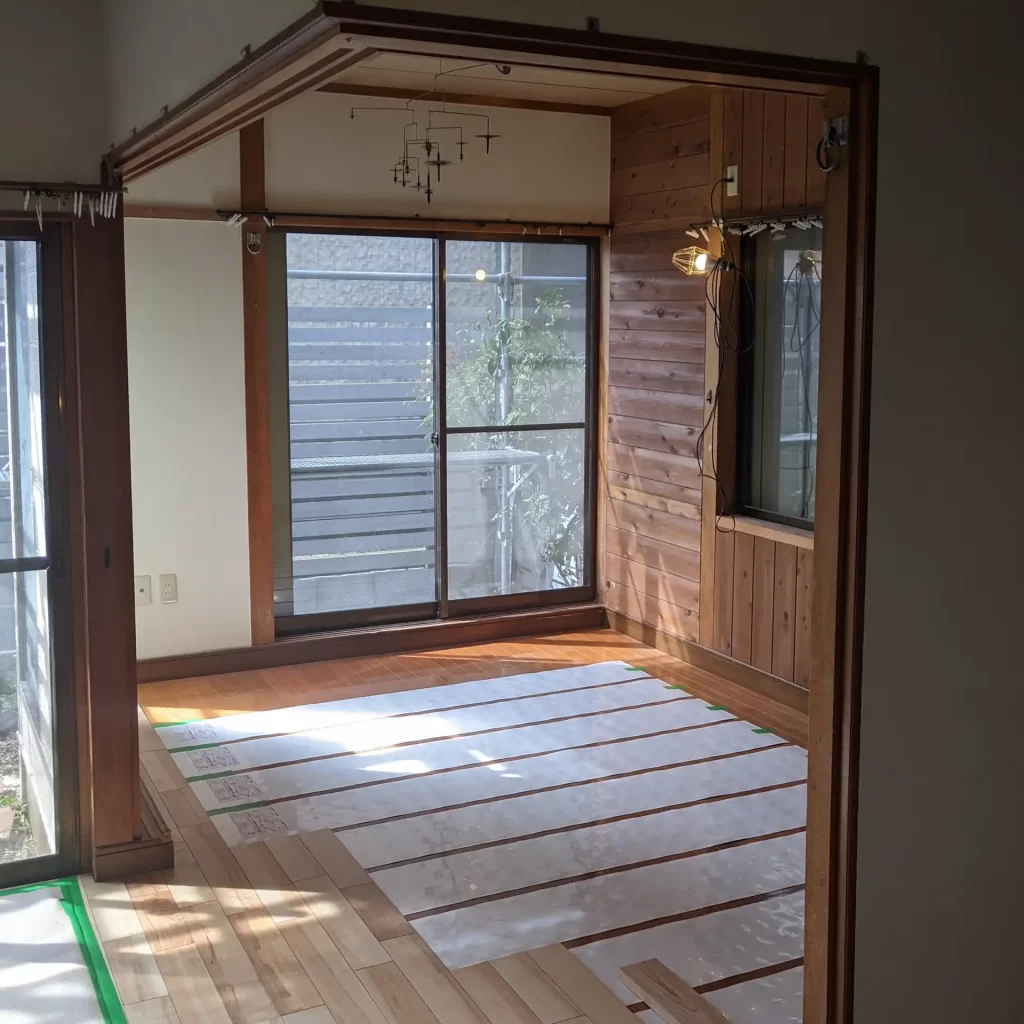 床暖房を施工している風景。床暖房はシート状の電気式。既存のフロアの上に設置して新設フロアを貼っていきます。