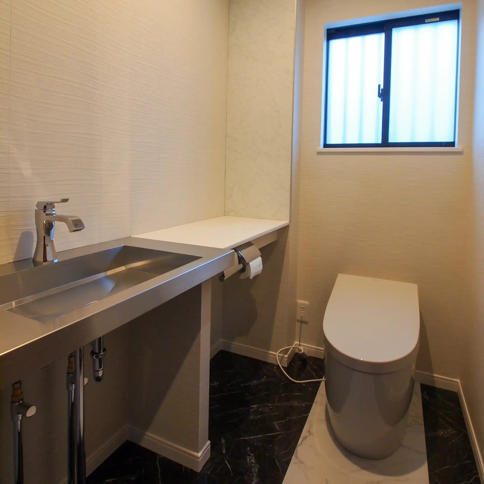 大蒲の家のトイレ。便器を中心に床を貼り分けています。手洗いはステンレス製でお施主様が直接仕入れてきたものを取付けています。