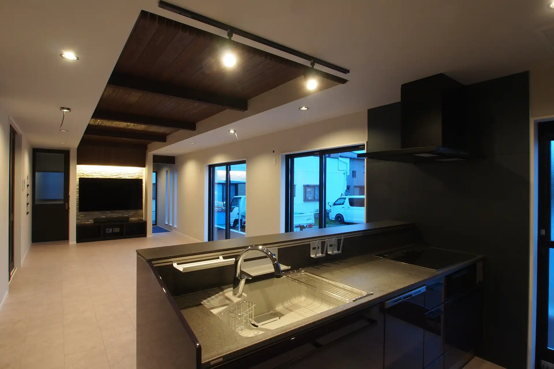 大蒲の家のキッチンからリビングダイニングをみた画像。夕方に撮影しました。照明はダウンライトをメインにキッチンにはスポットライトで手元を明るくしています。